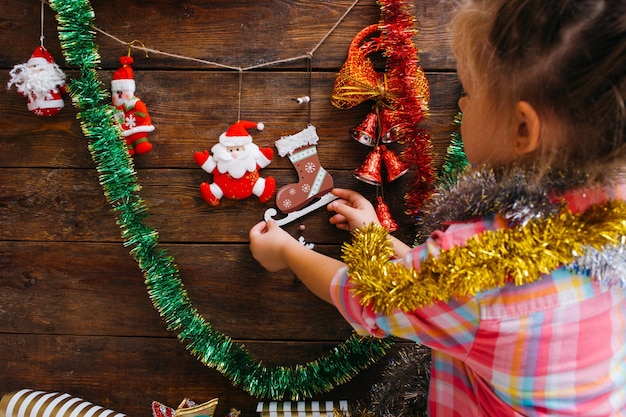 Esperando pela decoração da casa de Natal Menina criativa decorando o fundo de madeira Criança no conceito festivo do processo de arte