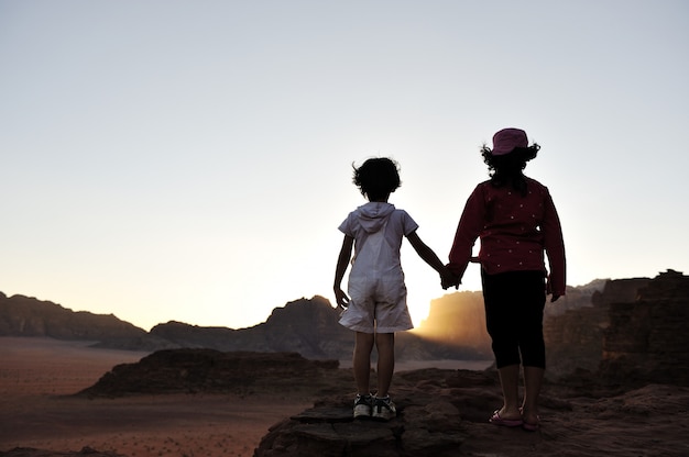 Esperando la puesta de sol en el desierto, hermano y hermana juntos visitando África. Niño y niña