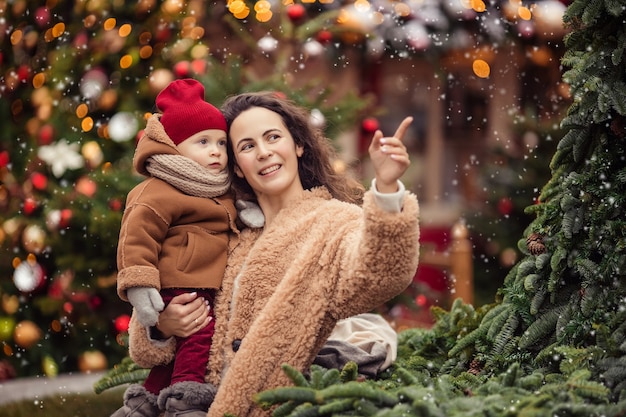 esperando las vacaciones de año nuevo. feliz mamá alegre con niños en un paseo en invierno en una calle decorada de Navidad.