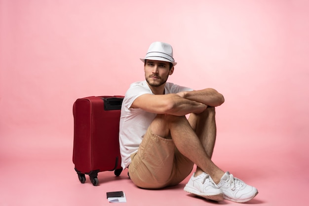 Esperando el vuelo. Viajero hombre sentado en el suelo con maleta.