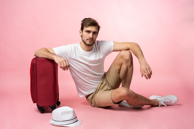 Esperando el vuelo. Viajero hombre sentado en el suelo con maleta.