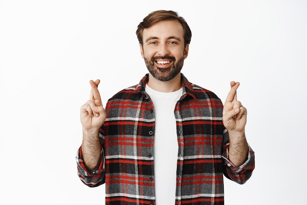 Esperanza Hombre optimista sonriente con barba que cruza los dedos pide un deseo anticipando algo anhelando saborear el fondo blanco