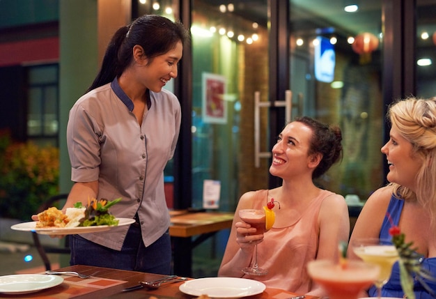 Espero que disfrute de su comida Captura recortada de una camarera que atiende a los clientes en un restaurante