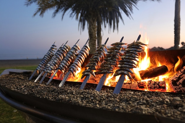 Foto espesor de sardina con fuego al atardecer comida típica mediterránea de la ciudad de málaga