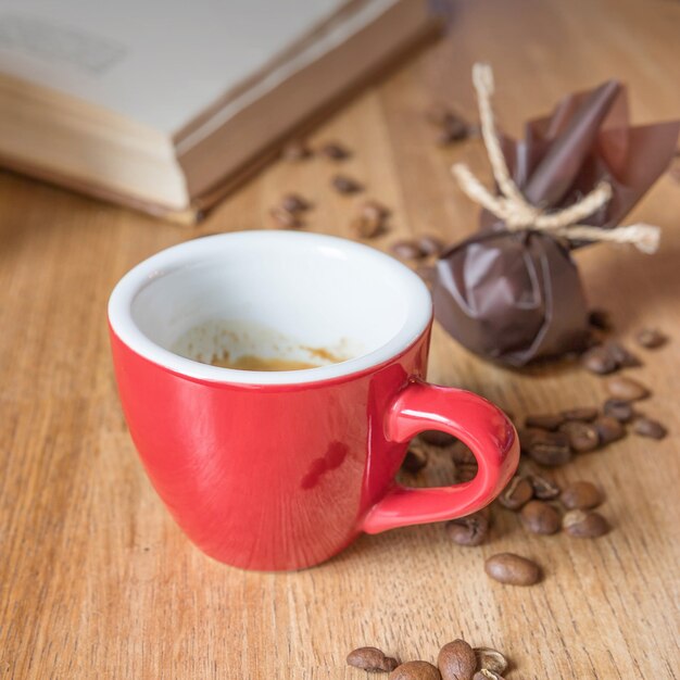 Espesso en una taza roja caramelos y un libro sobre una mesa en caf