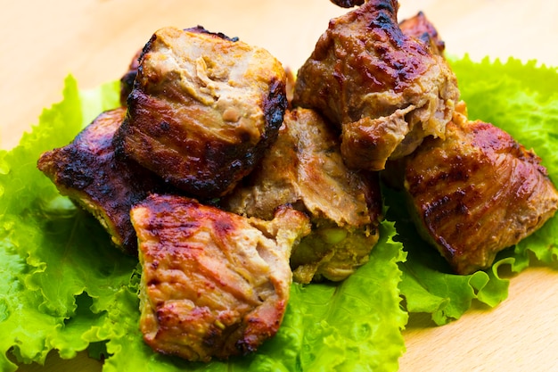 Espetada de carne de porco em uma mesa de madeira.