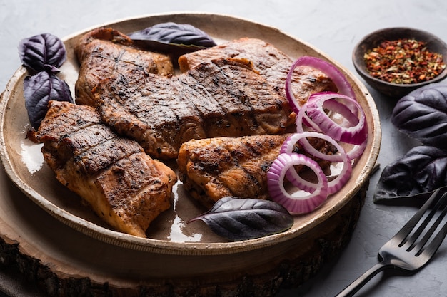 Foto espetinho de bagre shashlik com peixe assado em um prato redondo com cebola roxa e manjericão
