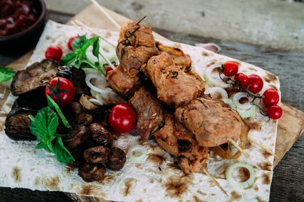 Espetinho de carne de porco com legumes e close up de molho de tomate em uma mesa de madeira