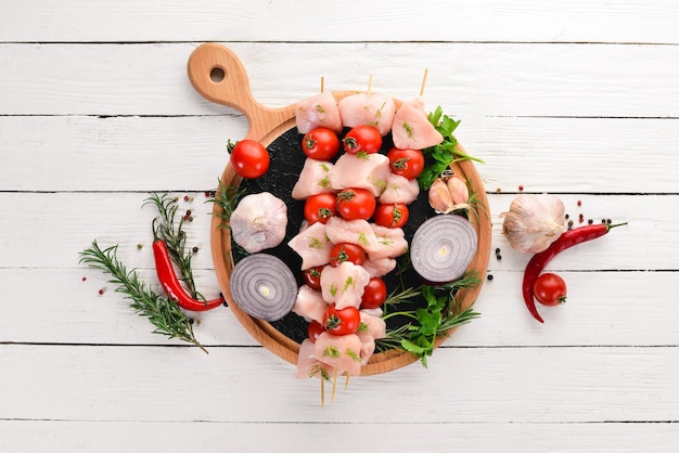 Espetinho de frango cru com tomate cereja Churrasco Em um fundo branco de madeira Vista superior Espaço para cópia gratuita