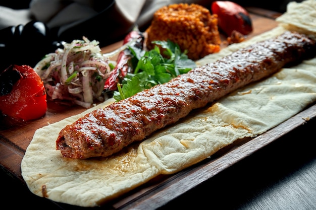 Espetinho de lula de cordeiro turco grelhado com legumes grelhados, cebola e arroz na tábua de madeira