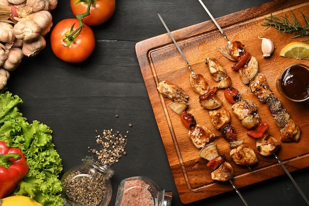 Espetinhos de frango caseiro com tomate pimentão e cebola na mesa de madeira preta