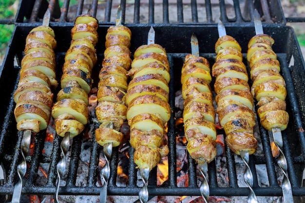 Espetos de batata na brasa na grelha ao ar livre.