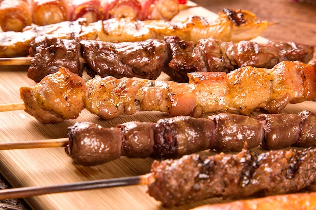 Foto espetos de bife variados em cima de uma tábua