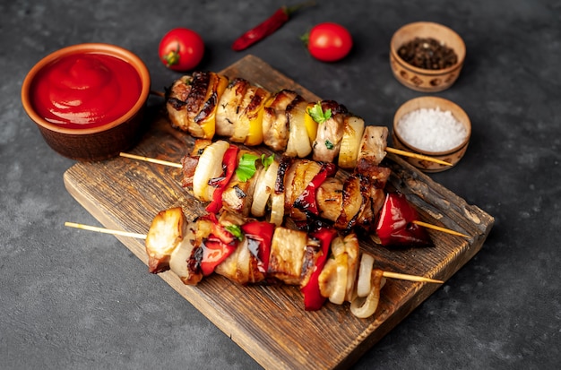 Espetos de carne com legumes grelhados em uma tábua sobre um fundo de pedra