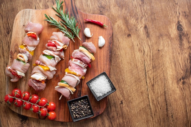 Espetos de carne crua com legumes em fundo de madeira com espaço de cópia para o seu texto