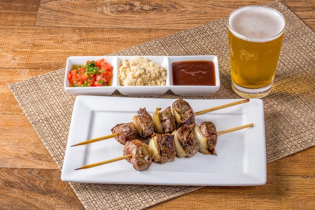 Espetos de carne na mesa de madeira