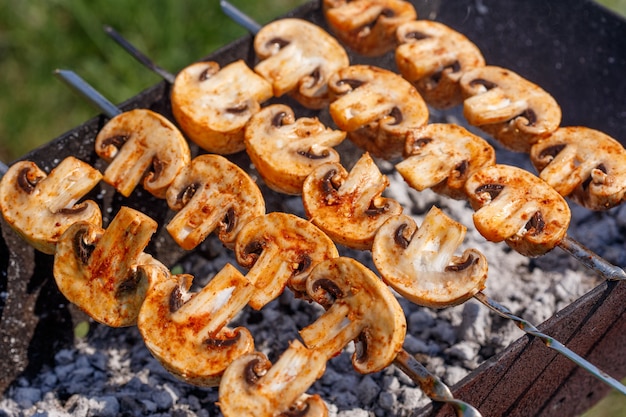 Espetos de churrasco com delicioso kebab de cogumelos champignon grelhado em um braseiro