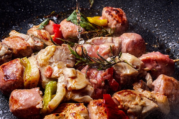 Espetos de frango cozidos em panela de pedra e vinho branco caindo de cima. Um ramo de alecrim é adicionado para dar sabor.