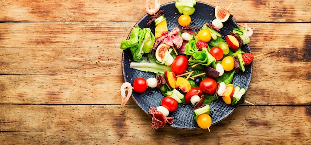 Espetos de madeira com carne de camarão e frutas