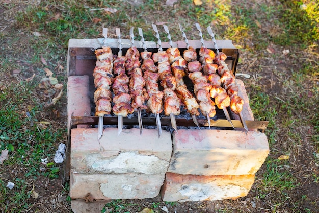 Espetos de porco são fritos em espetos sobre carvão em uma grelha de tijolos caseiro Delicioso jantar de churrasco no fim de semana