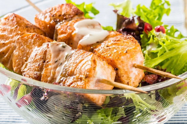 Espetos de salmão grelhados com salat de alface e óleo de oliva com sementes de pomehranate. Comida de peixe saudável com frutas e vegetais.