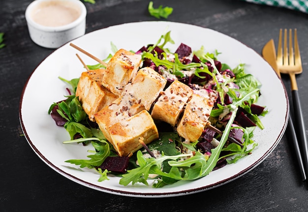 Espetos de tofu assado em molho e salada de beterraba rúcula com molho de iogurte vegetal conceito de comida vegana saudável comida saudável