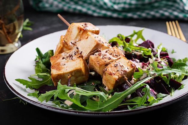 Espetos de tofu assado em molho e salada de beterraba rúcula com molho de iogurte vegetal Conceito de comida vegana saudável Comida saudável