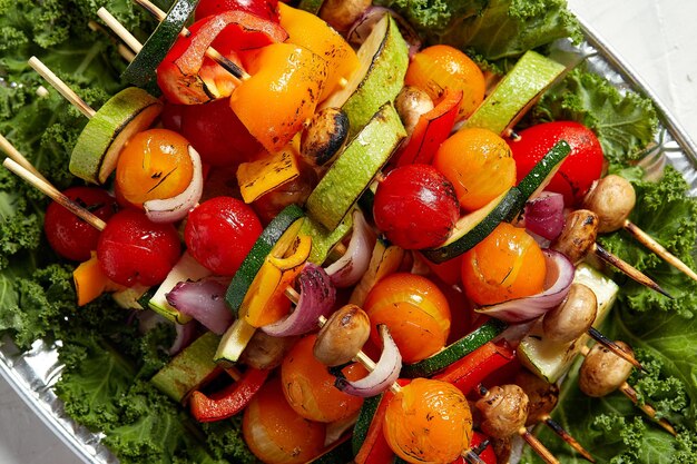 Espetos vegetarianos com ervas secas em espetos de madeira de cogumelos de cebola tomate abobrinha em um prato