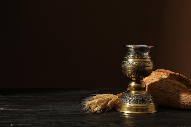 Foto espigas de pan de cruz de madera y taza en espacio de fondo marrón para el texto