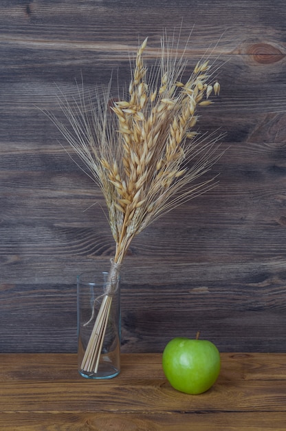 Espigas de trigo y cebada en un jarrón sobre el fondo de tablas de madera.