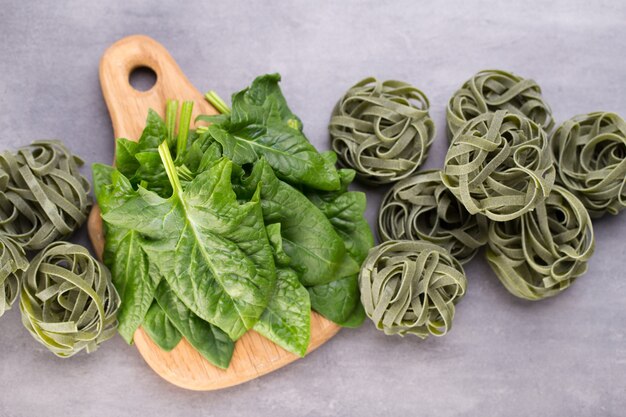 Espinaca fresca con pasta verde sobre fondo gris.