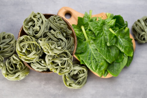 Espinaca fresca con pasta verde sobre fondo gris.