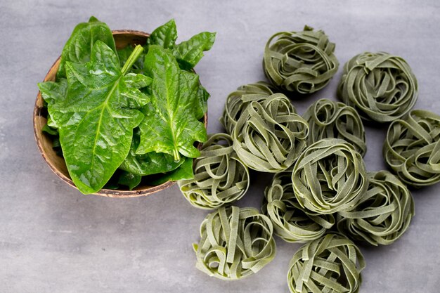 Espinaca fresca con pasta verde sobre gris.