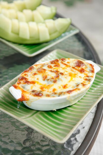 Espinacas al horno con queso en taza de cerámica en la mesa