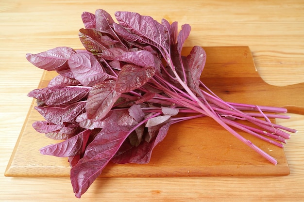 Espinacas rojas orgánicas frescas o Amaranthus Dubius en una tabla de cortar de madera