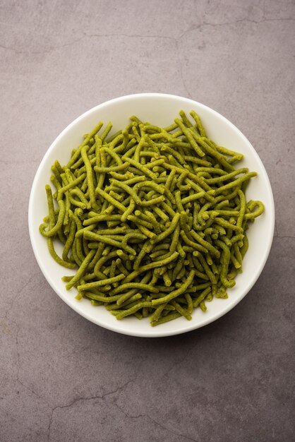 Espinafre ou palak sev são macarrão salgado frito crocante. Caseiro Shev ou namkeen verde espesso e fino é um lanche indiano clássico. servido em uma tigela ou prato