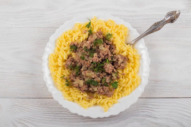 Espirales de pasta boloñesa Tagliatelle con carne picada en un plato blanco sobre un fondo de madera