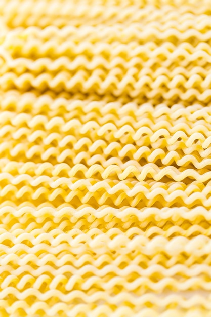 Espirales de pasta larga amarilla orgánica sobre un fondo blanco.