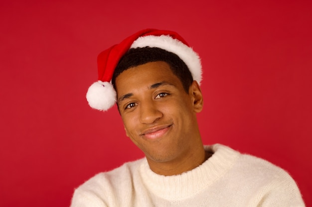 Foto espirito natalino. jovem sorridente com um suéter branco e chapéu de papai noel