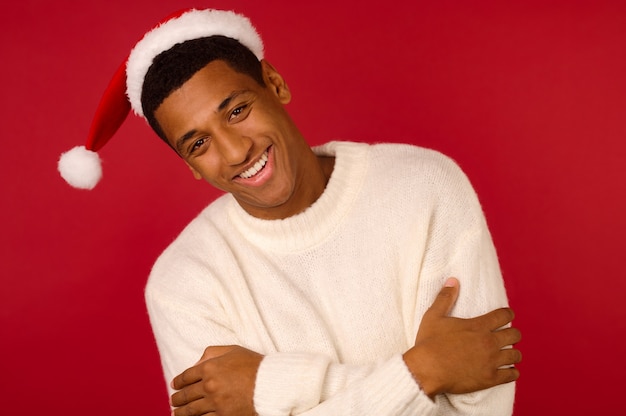 Espirito natalino. Jovem sorridente com um suéter branco e chapéu de Papai Noel