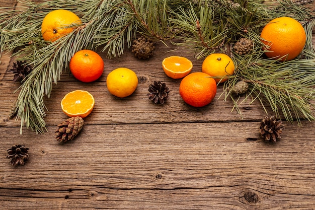 Espíritu Navidad en mesa de madera. Naranjas frescas, mandarinas, ramas de pino y conos. Decoraciones de la naturaleza, tableros de madera vintage