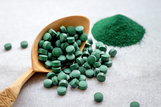 Espirulina de algas verdes en tabletas y polvo sobre un fondo de arpillera. Proteína vegetal