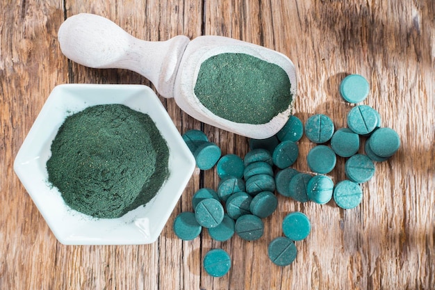 Espirulina en polvo y tabletas sobre fondo de madera