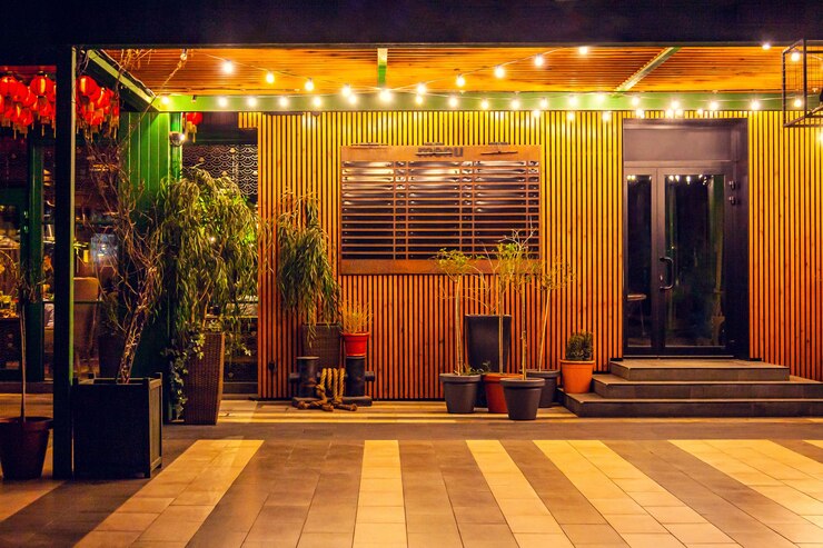 Esplanada de verão no café à noite, decorada com guirlandas, com plantas em vasos, barris no chão de ladrilhos