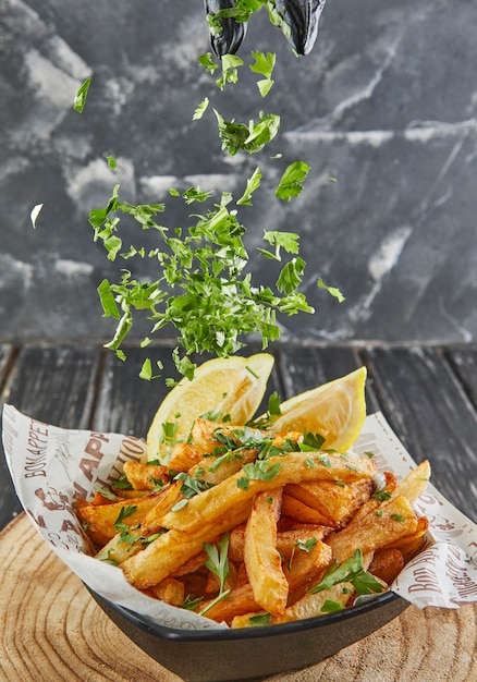 Foto espolvoree perejil sobre patatas con perejil y limón frito en aceite sobre tabla de madera