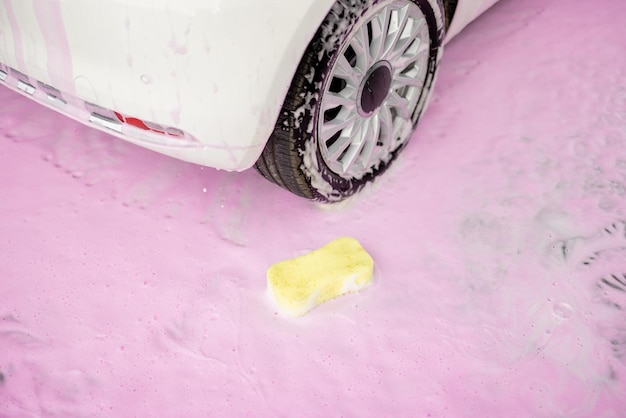 Esponja amarilla en espuma rosa en lavado de autos