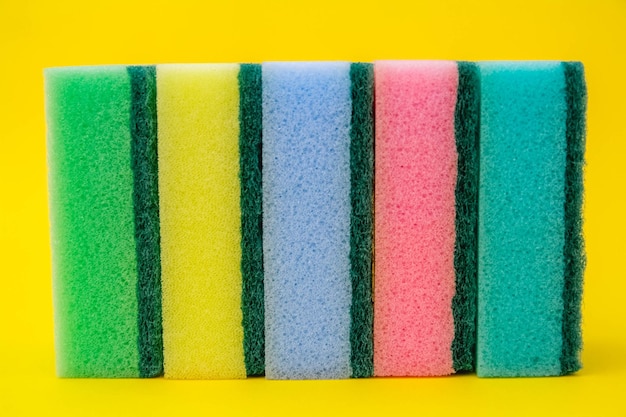 Foto esponja de espuma de borracha multicolorida para limpeza e lavagem de pratos em fundo amarelo