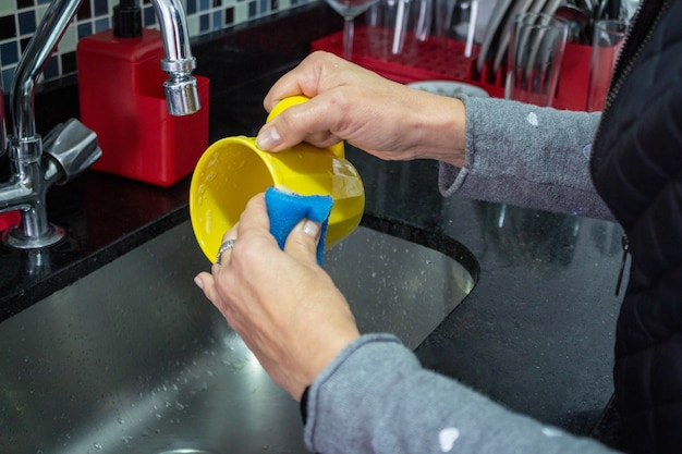 Esponja lavando louça em caneca amarela foco seletivo