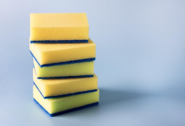 Esponjas amarillas para lavar platos en el espacio de copia horizontal de fondo azul
