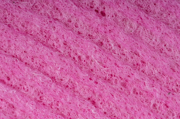 Esponjas de limpeza doméstica close-up. textura de detalhe de esponja, textura de esponja perto do fundo. textura de esponja vermelha de celulose. malha de arame rosa sobre fundo de superfície de esponja